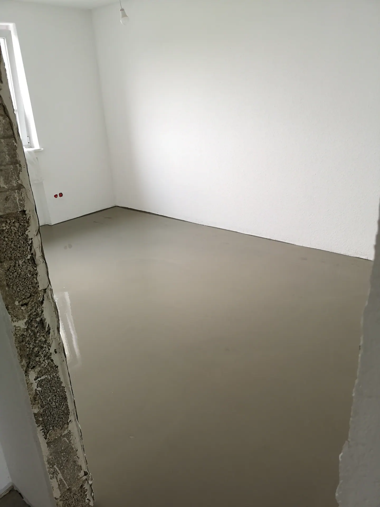 Raum mit vorbereitetem Boden und weißen Wänden